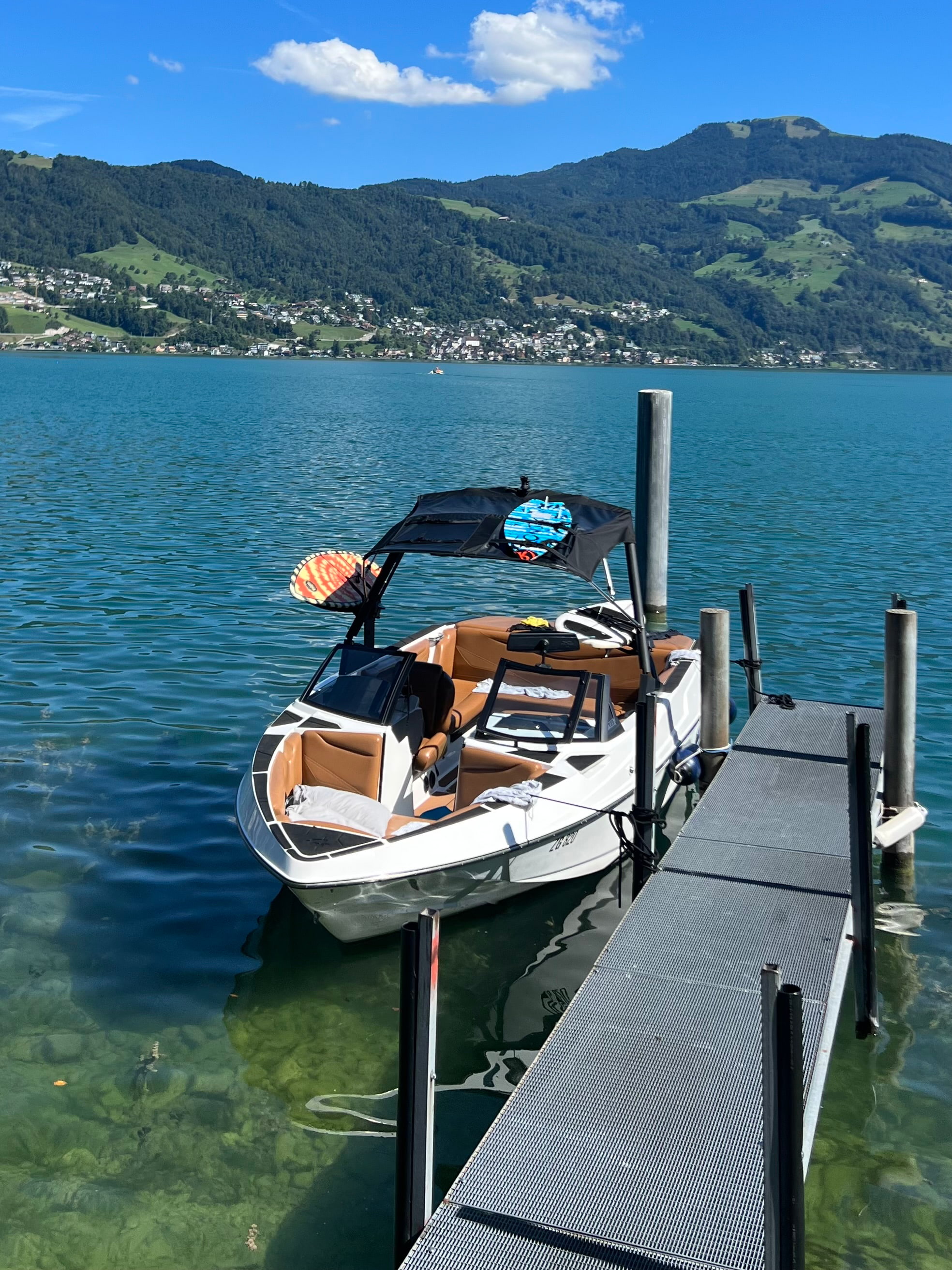 Frontal view of Axis wakeboat docked on Lake Zug with Mt. Rigi