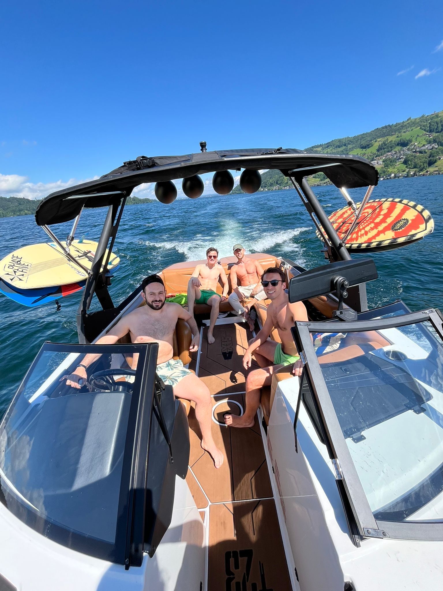 Group of guys on the Axis wakeboat with surfboards on Lake Zug